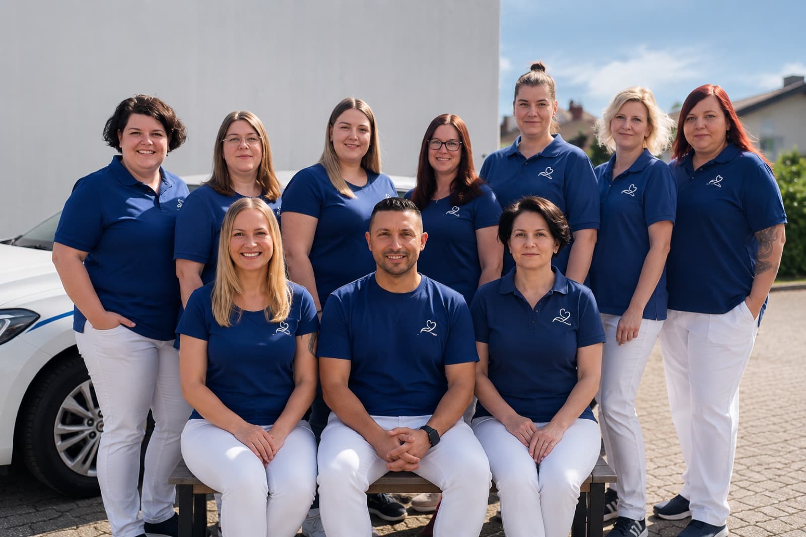 Das Team von SAV Pflegeleicht vor einem Dienstfahrzeug